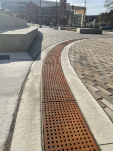 Cast iron trench grate with rounded edge holes in a grid pattern.