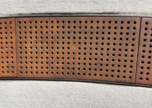 Cast iron trench grate with rounded edge holes in a grid pattern.