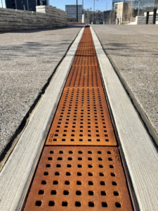 Cast iron trench grate with rounded edge holes in a grid pattern.