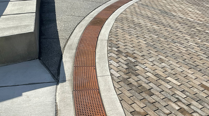 Cast iron trench grate with rounded edge holes in a grid pattern.