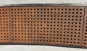 Cast iron trench grate with rounded edge holes in a grid pattern.