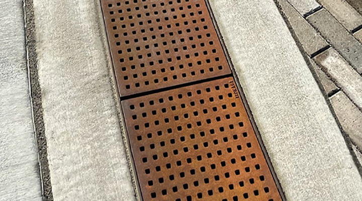 Cast iron trench grate with rounded edge holes in a grid pattern.
