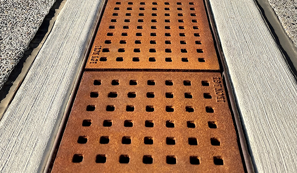 Cast iron trench grate with rounded edge holes in a grid pattern.