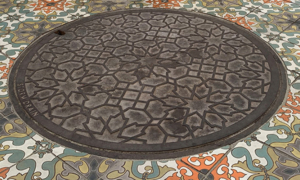 Decorative cast iron manhole cover with Spanish-influenced tiles surrounding it