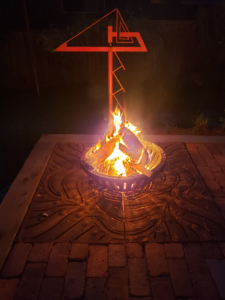 Decorative cast iron tree grate in Kelp pattern used as base for outdoor fire pit