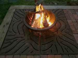 Decorative cast iron tree grate in Kelp pattern used as base for outdoor fire pit