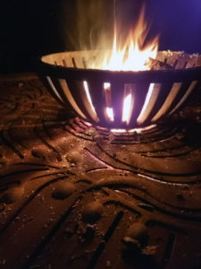 Decorative cast iron tree grate in Kelp pattern used as base for outdoor fire pit