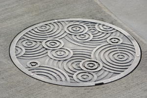 Decorative cast aluminum manhole cover in Oblio pattern