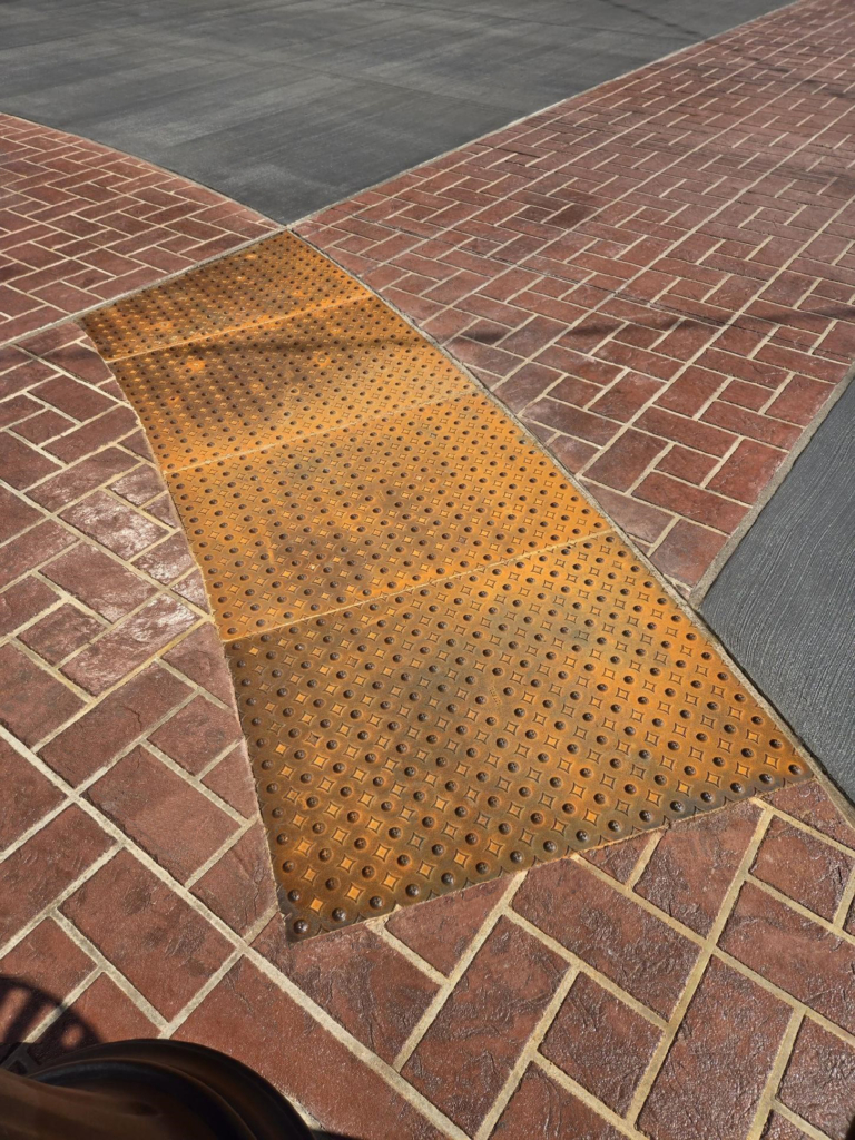 Cast iron detectable warning plates with decorative Interlaken pattern by Iron Age Designs.
