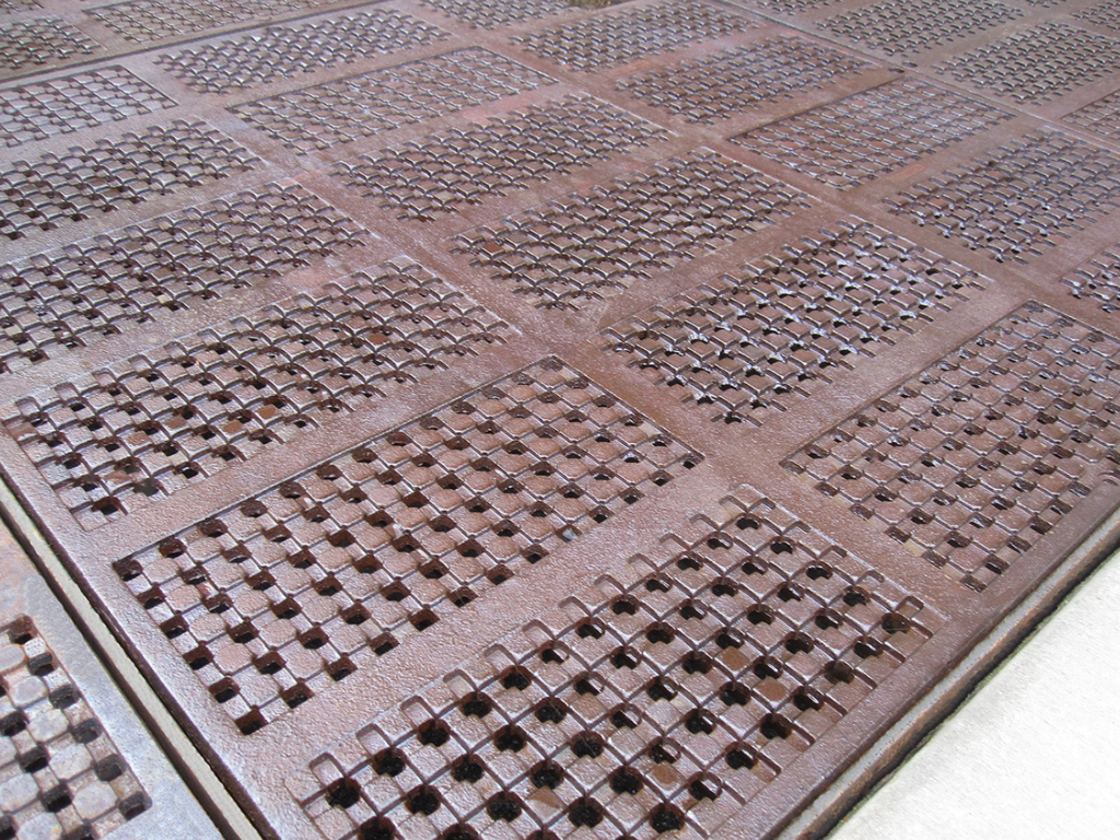 Cast iron grate panel in decorative Explora pattern by Iron Age Designs, Arrayed as a large tree grate.