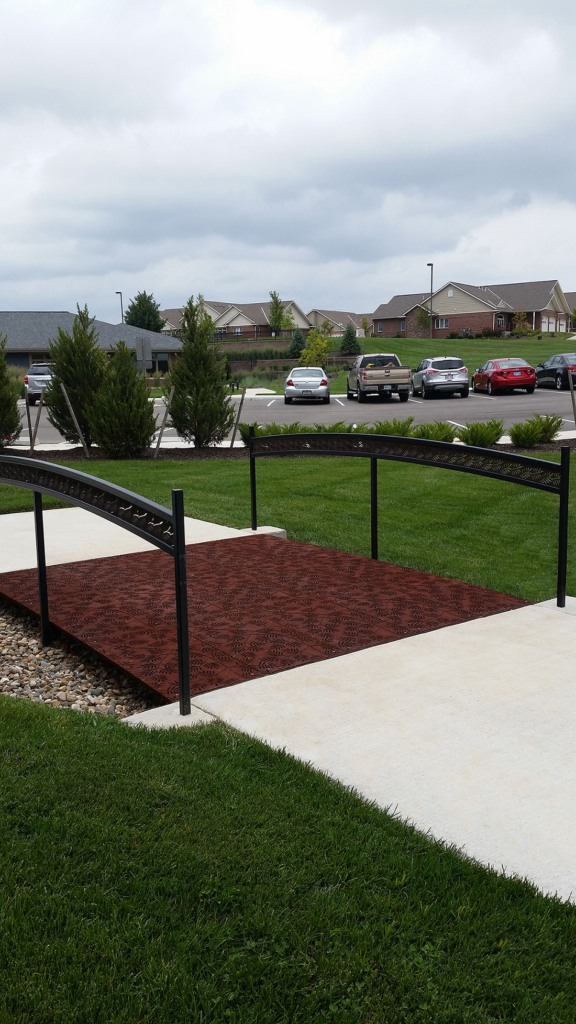 Cast iron grates in decorative Locust pattern by Iron Age Designs. Arrayed as a pedestrian bridge with matching laser cut handrail.