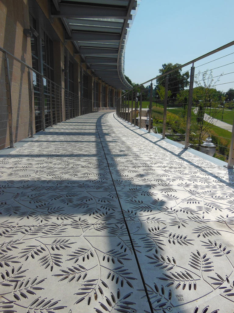 Cast aluminum grates in decorative Locust pattern by Iron Age Designs. Arrayed as a pedestrian bridge deck.