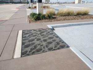 Cast iron grates in decorative Oblio pattern by Iron Age Designs. Arrayed as large stormwater inlet.