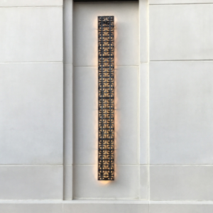 Cast iron, powder coated Carbochon drain grate shown used as lighting sconce on outside of building