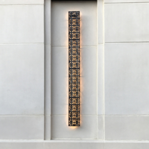 Cast iron, powder coated Carbochon drain grate shown used as lighting sconce on outside of building