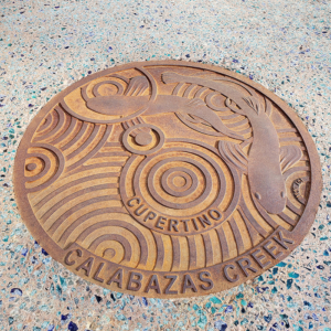 Cast iron custom plaque for Calabazas Creek with fish swimming over circular Oblio pattern