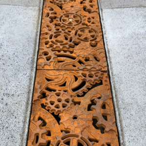 Decorative cast iron trench grates featuring interlocking gear pattern