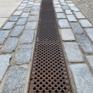 Decorative cast iron trench grate with grid pattern topped by 4-petal flowers