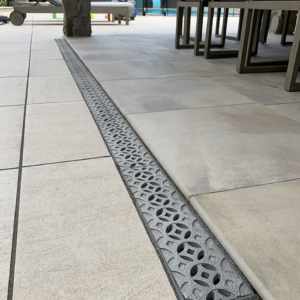 Decorative cast aluminum trench grates with Interlaken pattern installed in pool patio