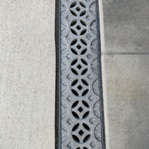 Decorative cast aluminum trench grates with Interlaken pattern installed in pool patio