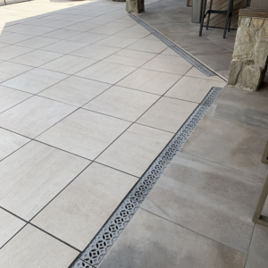 Decorative cast aluminum trench grates with Interlaken pattern installed in pool patio