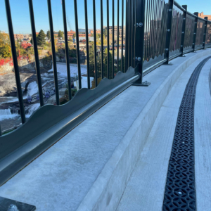 Decorative cast iron trench grates in Interlaken pattern with black powder coat finish.