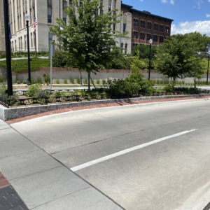 Decorative planter in road median on college campus, surrounded by custom cast iron planter fence.