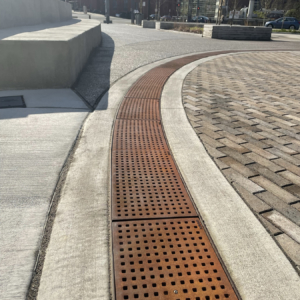 Cast iron trench grate with rounded edge holes in a grid pattern.