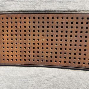 Cast iron trench grate with rounded edge holes in a grid pattern.