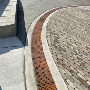 Cast iron trench grate with rounded edge holes in a grid pattern.