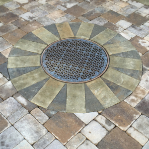 Decorative cast iron catch basin grate surrounded by pavers