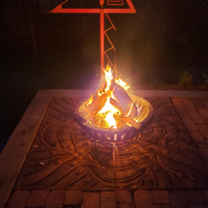 Decorative cast iron tree grate in Kelp pattern used as base for outdoor fire pit