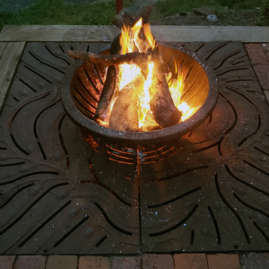 Decorative cast iron tree grate in Kelp pattern used as base for outdoor fire pit