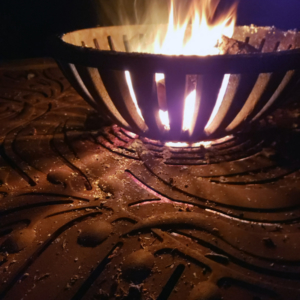 Decorative cast iron tree grate in Kelp pattern used as base for outdoor fire pit