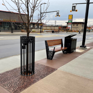 Decorative cast iron tree grate, powder coated tree guard and laser-cut steel bench ends in matching Minnione pattern