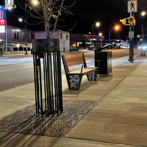 Decorative cast iron tree grate, powder coated tree guard and laser-cut steel bench ends in matching Minnione pattern