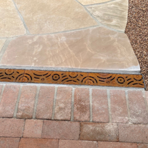 Decorative cast iron trench grate installed in paver patio