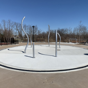 Cast iron radius trench grate with powder coat finish in ellipse shape around a spray park