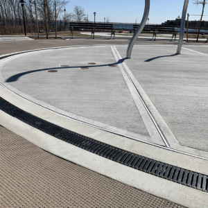 Cast iron radius trench grate with powder coat finish in ellipse shape around a spray park