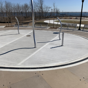 Cast iron radius trench grate with powder coat finish in ellipse shape around a spray park