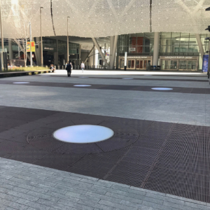 Cast iron grates surrounding LED lights, all installed in a pedestrian plaza