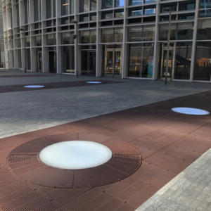 Cast iron grates surrounding LED lights, all installed in a pedestrian plaza