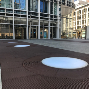 Cast iron grates surrounding LED lights, all installed in a pedestrian plaza