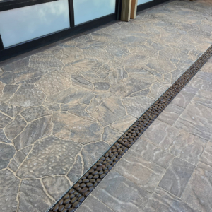 Decorative cast iron trench grates in River Rock pattern, installed in residential driveway