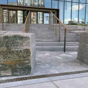 Decorative cast iron trench grate in Plex pattern installed in pavers in front of building entrance