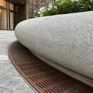 Decorative cast bronze radius trench grates in Que pattern surrounding circular planter in front of One Vanderbilt building