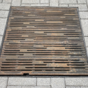 Decorative cast iron catch basin grate in Rain pattern