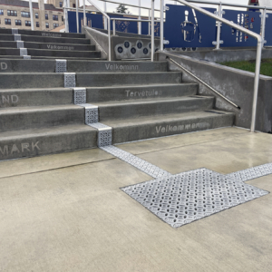 Cast aluminum trench drain grates in decorative Interlaken pattern, installed down center of concrete staircase