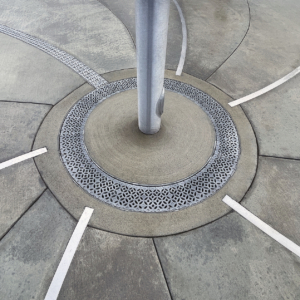 Cast aluminum radius trench drain grates in decorative Interlaken pattern, installed around flagpole