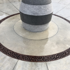 Cast iron radius trench drain grates in decorative Oblio pattern, installed around water feature